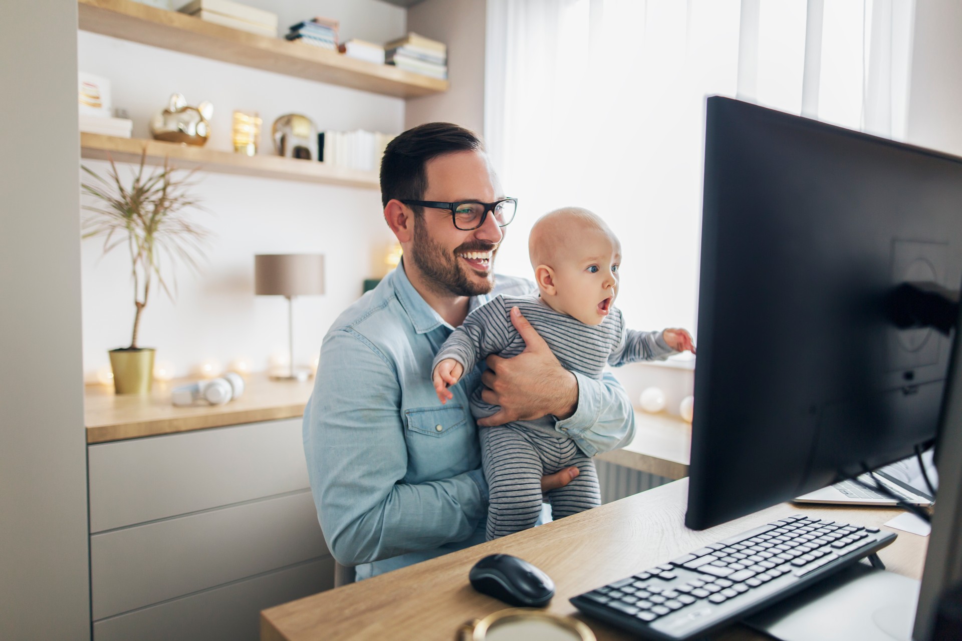 Young father working from home and holding his baby boy.